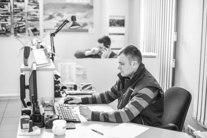 Man Working at a Computer in a Factory, Candid Moment – Corporate Industrial Image